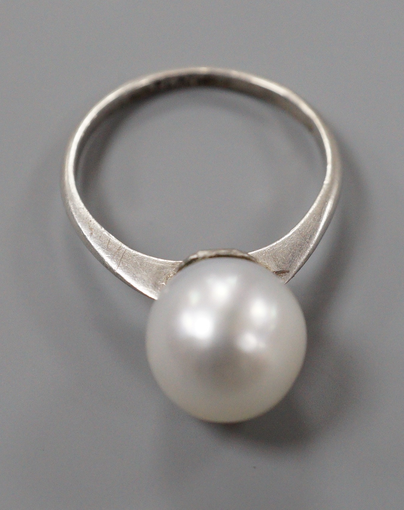 A white metal (stamped Plat) and single stone cultured pearl ring, size O, gross weight 4.1 grams.